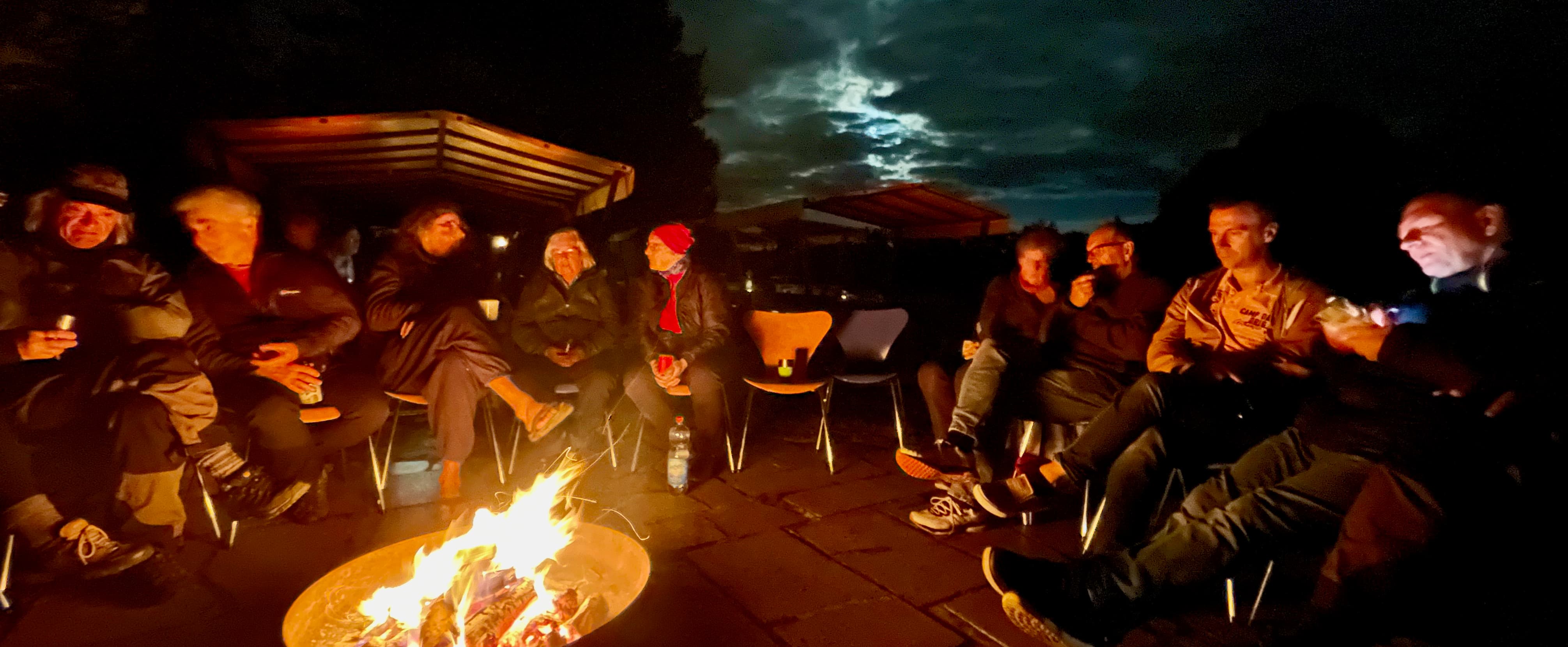 A group of cyclists sitting around a firepit